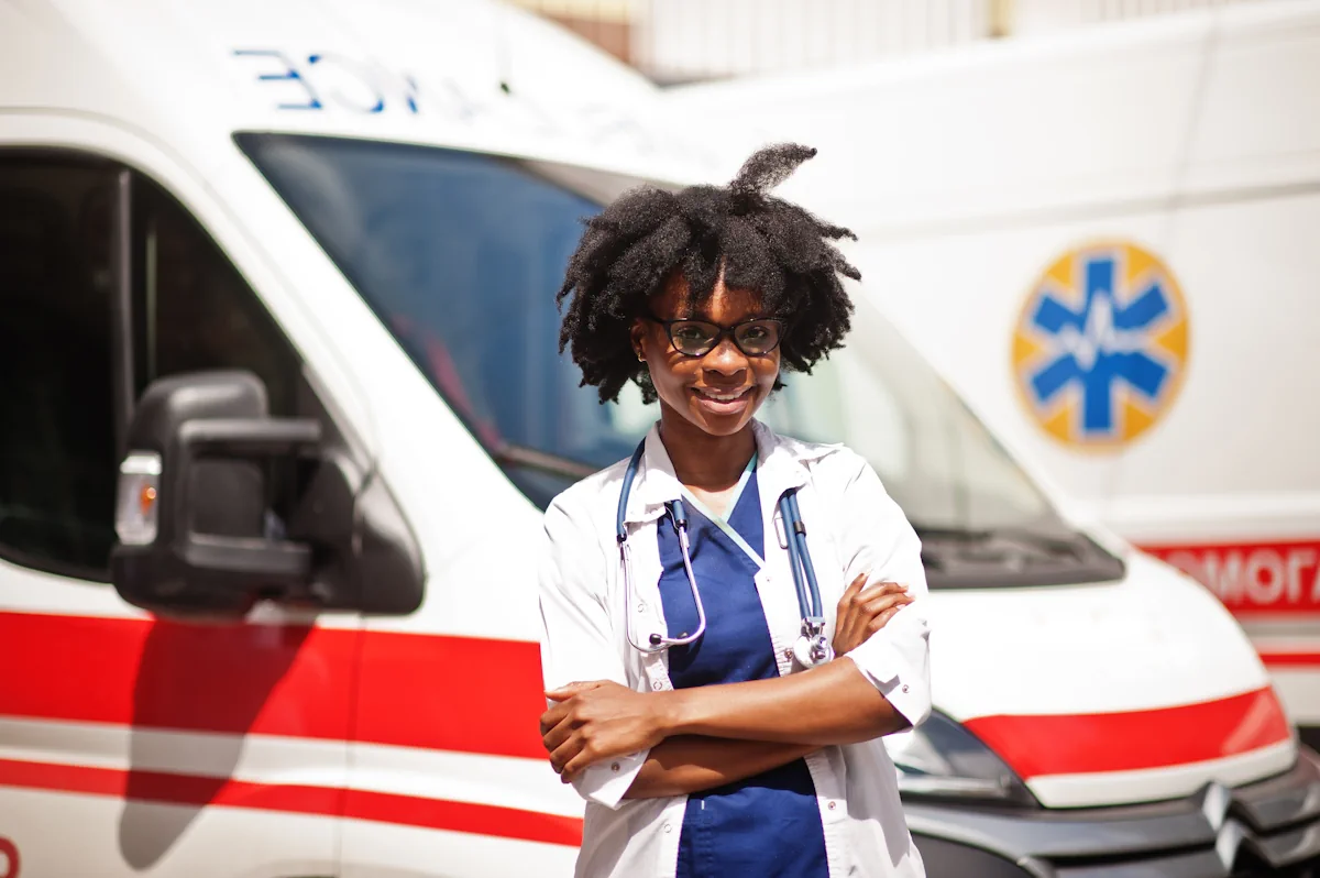 Une femme en blouse blanche devant une ambulance