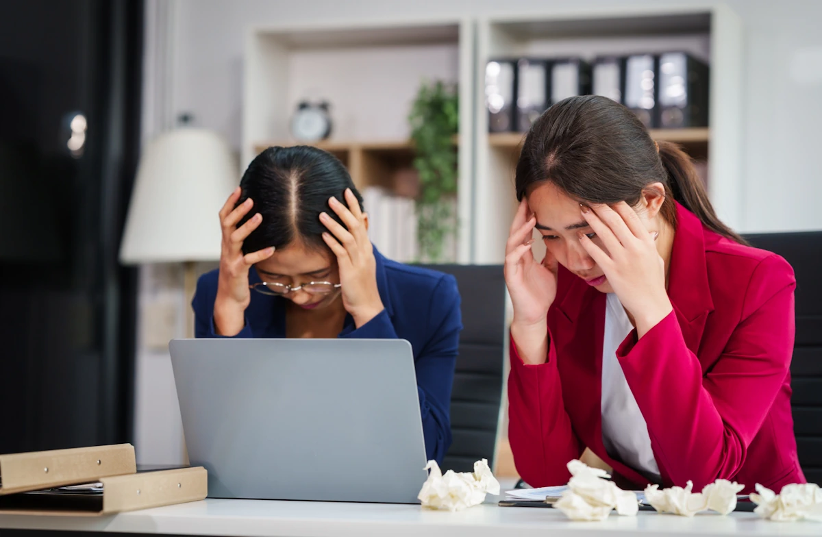 Deux femmes qui se tiennent la tête devant un écran d'ordinateur