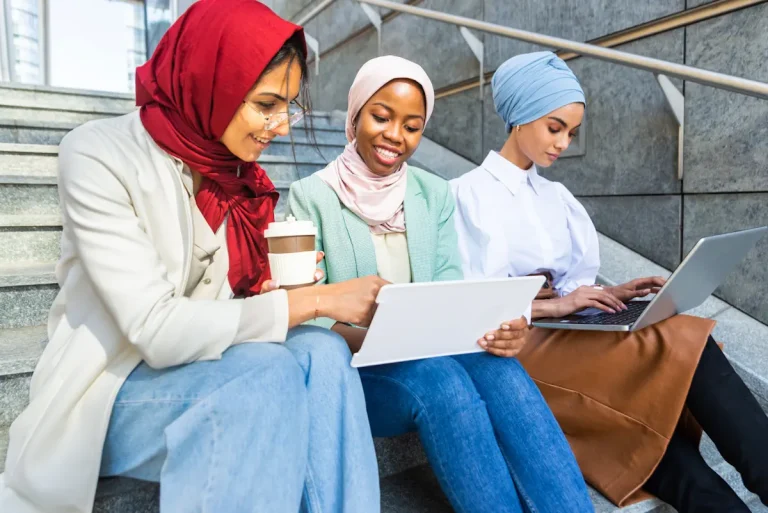 3 femmes assises sur des escaliers qui regarde des ordinateurs