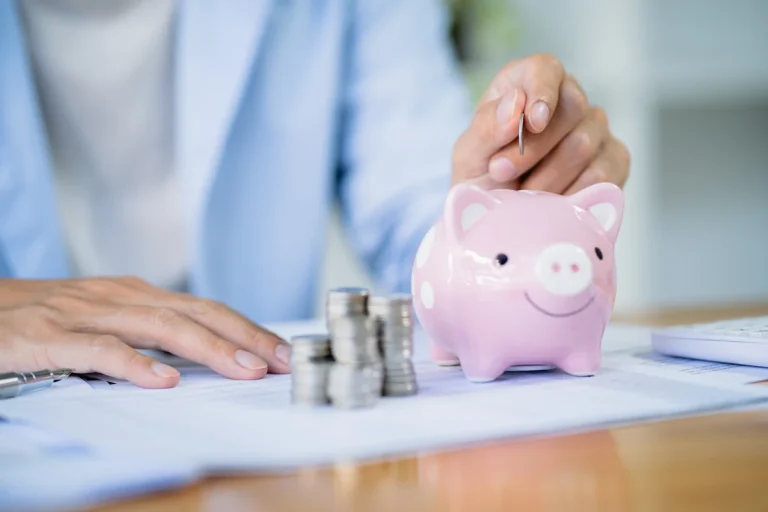 Une personne qui met des pièces dans une tirelire en cochon