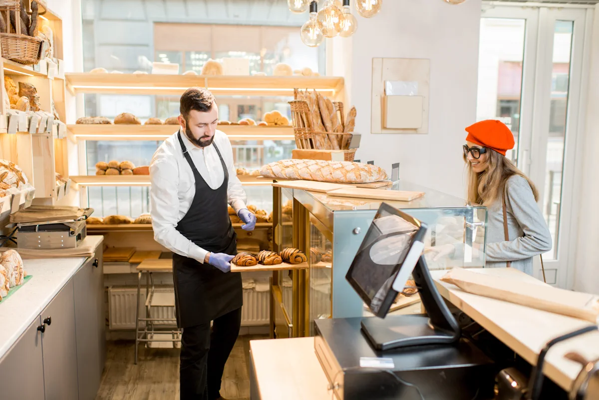 Un homme qui met des pains dans une vitrine de boulangerie