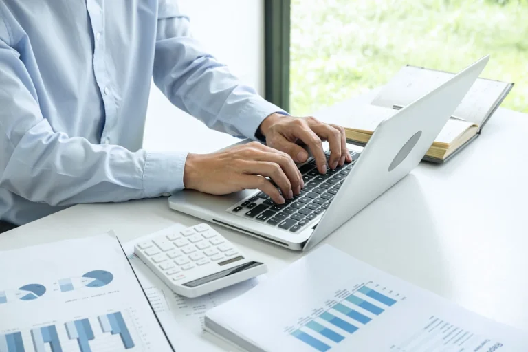 Un homme qui travaille sur un ordinateur à côté d'une machine à calculer