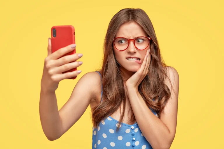 Une femme qui fait la grimace qui regarde un smartphone rouge