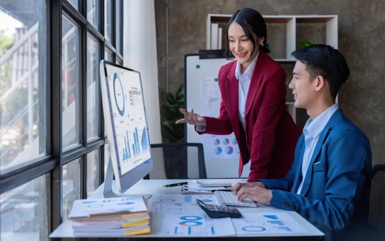 Une femme et un homme qui discute face à des écrans d'ordinateur