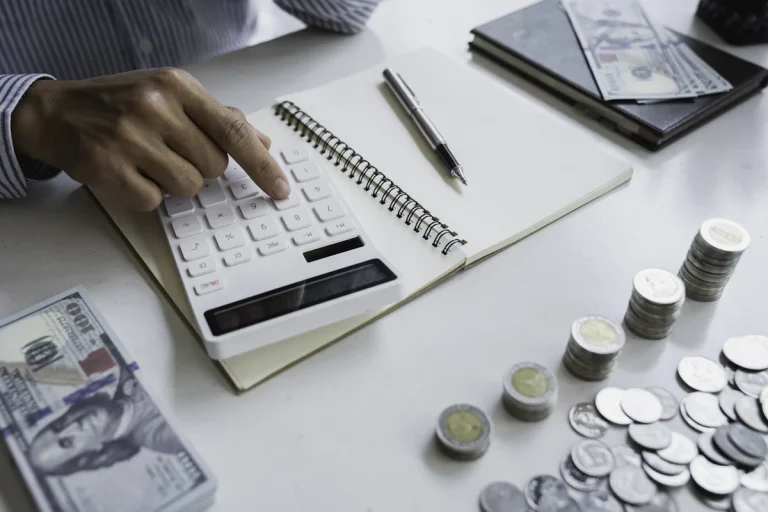 un homme qui calcule sur une calculatrice avec de l'argent posé sur la table