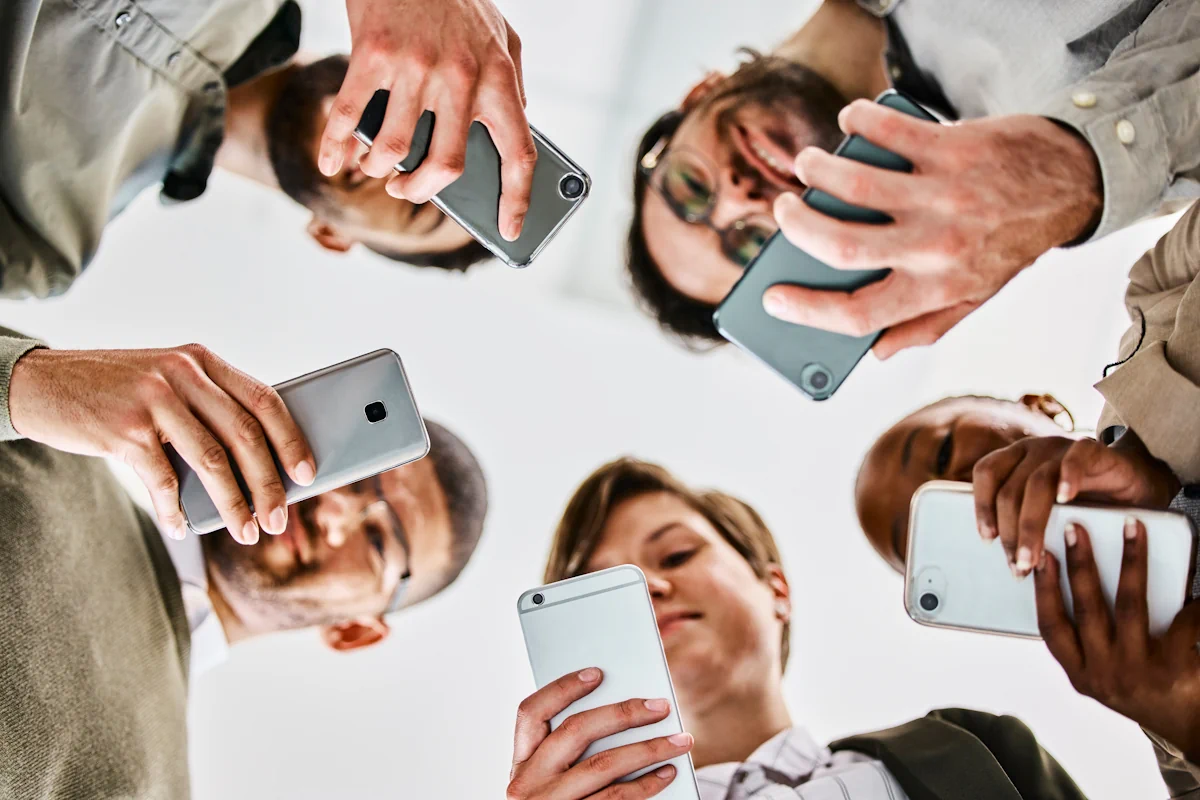 Un groupe de personne qui forme un rond et regarde leur téléphone