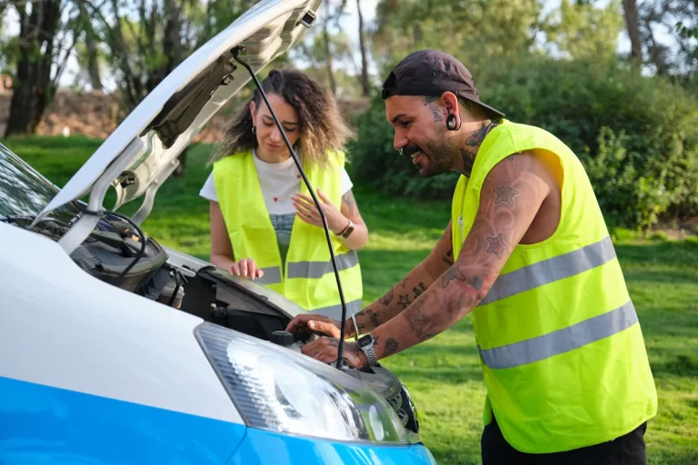 Un homme et une femme en gilet jaune qui regarde sous le capot d'une voiture